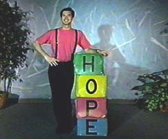 A man in a red shirt stands beside stacked boxes that spell HOPE.