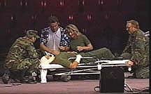 A depiction of a scene from the TV show "MASH" with four characters, in Army uniforms, caring for an injured person on a stretcher.