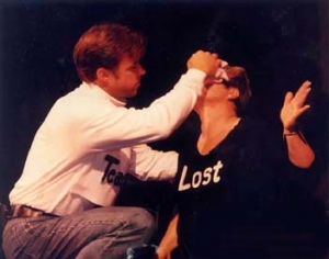 The character "Teacher" wipes the character "Lost's" forehead with a cloth.