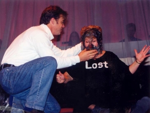 The character "Teacher" removes the mask from the character "Lost's" face.