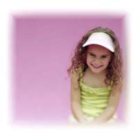 A young girl sitting down with a sun visor on.